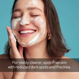 Smiling woman applying salicylic acid cleansing foam face wash lather for visibly clearer, spot-free skin